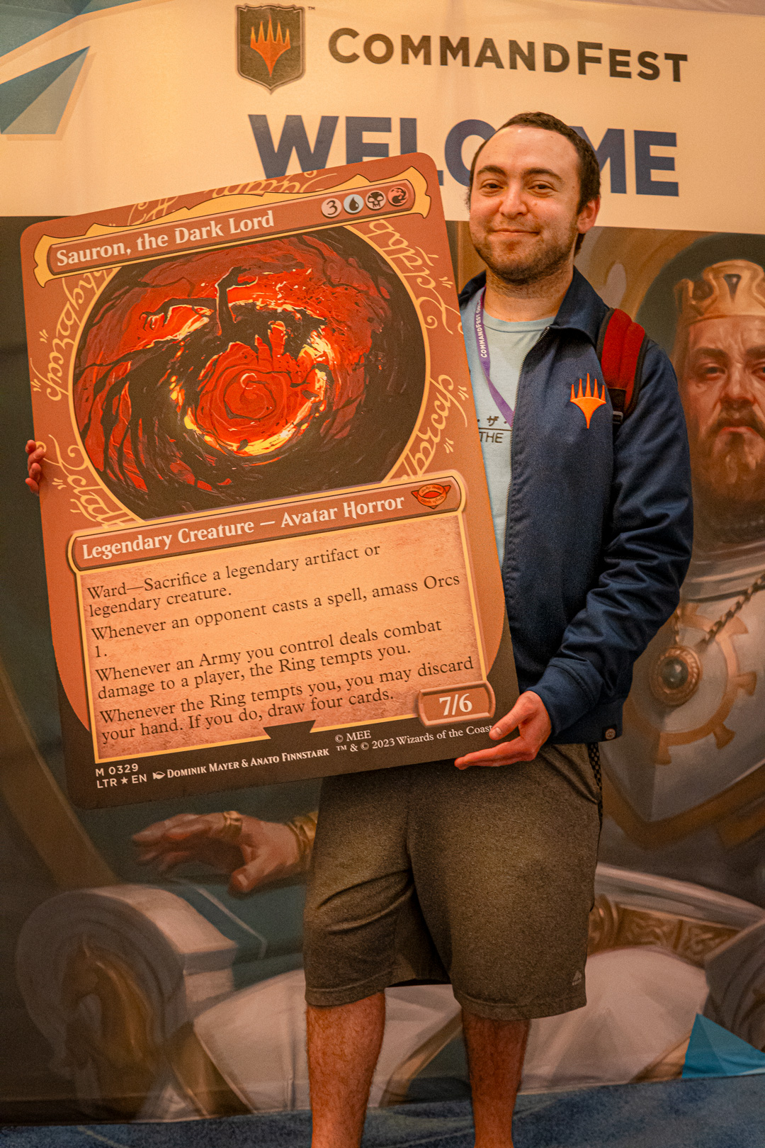 Player holding an oversized card of Sauron, the Dark Lord