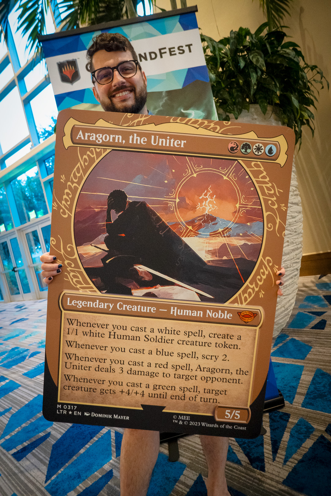 Player holding an oversized card of Aragorn, the Uniter