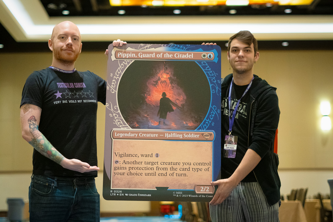 Player holding an oversized card of Pippin, Guard of the Citadel