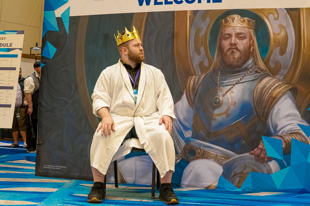 TheOneJame dressed as Kenrith the Returned King posing in front of banner of Kenrith